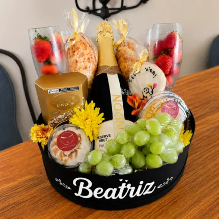 Cesta personalizada com Chandon, morangos, uvas, chocolates Lindor, doces gourmet e taças para presente.